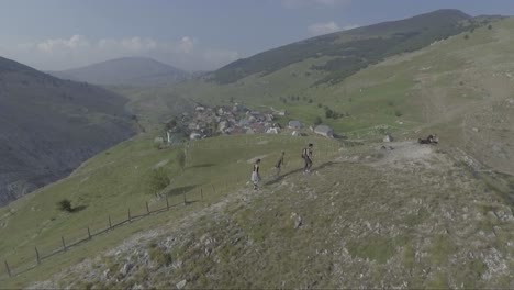 Aerial-of-people-walking-on-hilltop-near-ancient-quaint-Lukomir-village-in-Bosnia-former-Yugoslavia