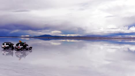 Aerial-of-people-and-jeeps-on-the-Uyuni-salt-flats-lake-with-perfect-reflections-in-Bolivia