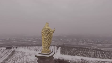 Vista-Aérea-of-golden-statue-of-Jesus-Christ-with-outstretched-arms-in-Fatima-Portugal-in-snowy-winter-weather