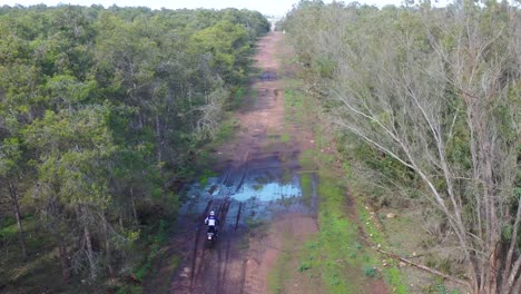 A-Dirt-Bike-Motorcycle-Rider-Drives-On-A-Backroad-Area-With-Some-Large-Water-Puddles-1