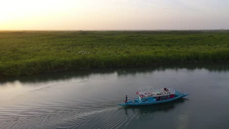 Schöne-Antenne-über-Ein-Kleines-Boot,-Das-Sich-Entlang-Des-Gambia-Flusses-In-Westafrika-Durch-Mangrovenwälder-Und-Gewundene-Kurven-Bewegt