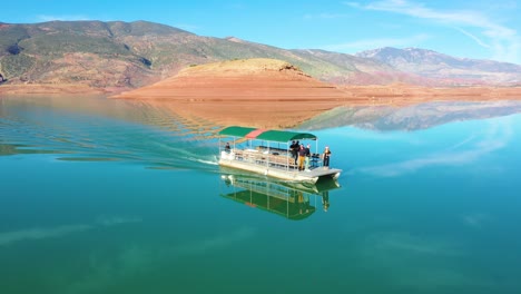 Pov-Antenne-Eines-Mannes,-Der-Von-Einem-In-Champagner-Getränkten-Touristenboot-Auf-Dem-See-Bin-El-Ouidane,-Marokko,-Springt