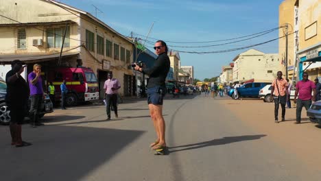 Un-Turista-Patina-Por-Una-Calle-En-Gambia,-África-Occidental-En-Una-Patineta