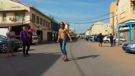A-Tourist-Skates-Down-A-Street-In-Gambia-West-Africa-On-A-Skateboard-1