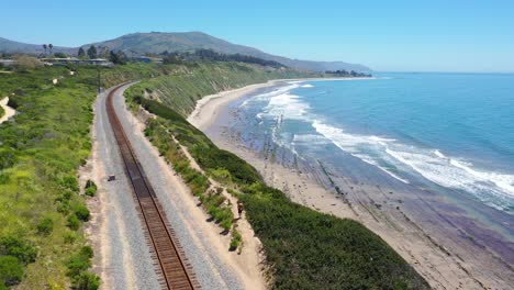 Aerial-Over-Man-Walking-On-Railroad-Tracks-Above-The-Pacific-Coast-Near-Carpinteria-Bluffs-Santa-Barbara-California