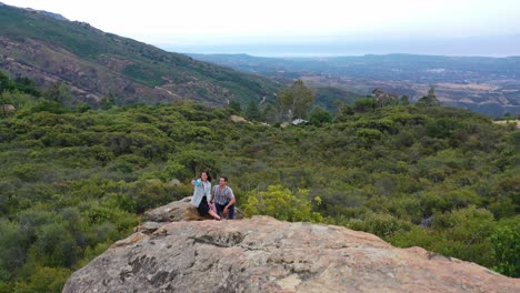 Ein-Mann-Und-Eine-Frau-Klettern-Auf-Einen-Felsen-Und-Machen-Selfie-Fotos-Mit-Blick-Auf-Santa-Barbara,-Kalifornien