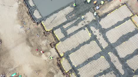 Top-Down-Aerial-Over-Construction-Site-With-Giant-Crane-And-Workers-Pouring-Concrete-Foundation-In-Ventura-California