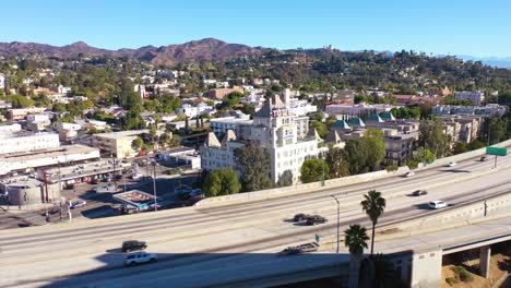 Aerial-Of-The-Hollywood-Tower-Hotel-With-The-Hollywood-Freeway-Foreground-And-Hollywood-Hills-Background