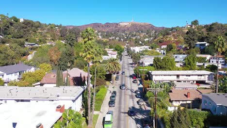 Aerial-Above-Beachwood-Drive-Palms-In-Hollywood-With-Cars-Driving-Up-Towards-Hollywood-Sign