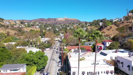 Aerial-Above-Beachwood-Drive-In-Hollywood-With-Cars-And-Bus-Driving-Up-Towards-Hollywood-Sign