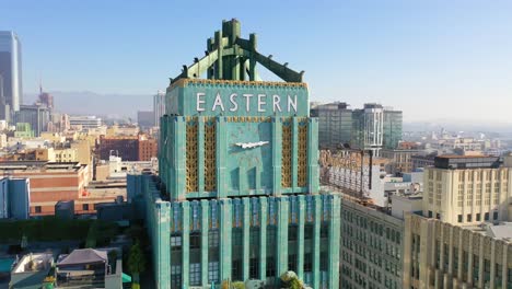 Aerial-Of-The-Historic-Eastern-Building-In-Downtown-Los-Angeles-With-Clock-And-Downtown-City-Skyline-Behind