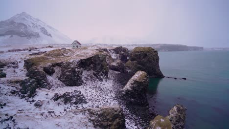 Ein-Haus-Mit-Blick-Auf-Den-Hafen-Von-Arnarstapi-Auf-Der-Isländischen-Halbinsel-Snaefellsne-Mit-Schnee-Auf-Dem-Boden-1-Ground