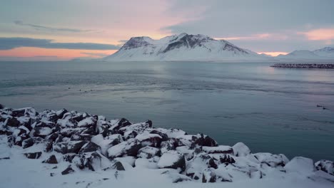 Snowy-banks-are-seen-on-the-Snaefellsne-Peninsula-in-Iceland-at-sunset-with-birds-swimming-in-the-water