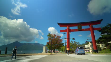 Vehicular-and-foot-traffic-pass-by-a-traditional-red-gate-at-Chuzenji-Lake-in-Nikko-Japan
