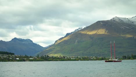 A-boat-is-seen-anchored-in-Lake-Wakatipu-with-mountains-in-full-view-in-Queenstown-New-Zealand
