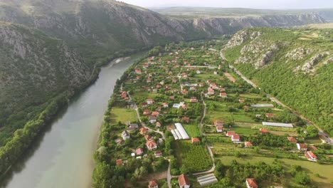 Eine-Luftaufnahme-Zeigt-Das-Dorf-Pocitelj-Bosnien-Und-Den-Fluss-Neretva,-Der-Daneben-Fließt