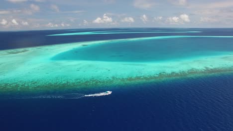 Eine-Luftaufnahme-Zeigt-Ein-Motorboot,-Das-An-Einem-Riff-Auf-Den-Malediven-Entlang-Fährt