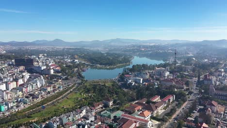 An-Aerial-View-Shows-Buildings-A-Radio-Tower-And-A-Lake-Of-Dalat-Vietnam