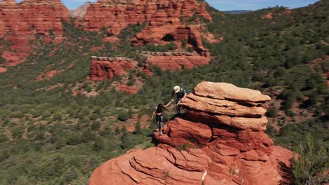 Aerial-of-two-lovers-couple-hiking-on-red-peak-butte-near-Sedona-Arizona