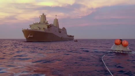 Vista-Aérea-Drone-Footage-Captures-the-Recovery-Of-A-Test-Re-Entry-Spacecraft-At-Sea-By-A-Large-Military-Boat-Sunset-2019