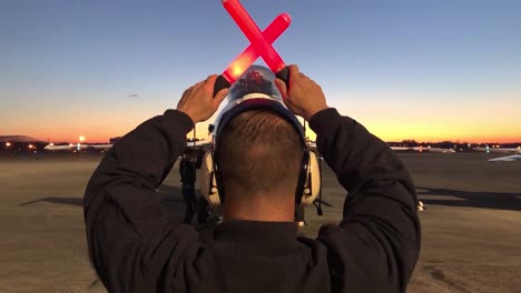 A-Man-With-Orange-Batons-Stands-In-Front-Of-An-Idle-F16-2019