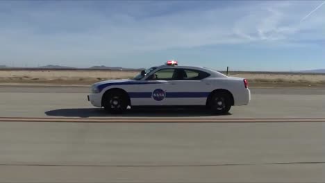 NASA-Er2-Kommt-Für-Eine-Landung-Und-Ein-2010-Dodge-Charger-Safety-Chase-Auto-Begleitet-Das-Flugzeug-Zu-Einer-Sicheren-Landung-Palmdale-2011