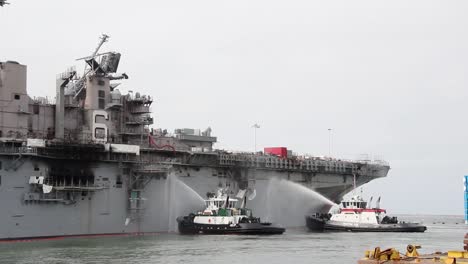 Tugboats-Spray-Water-On-the-Amphibious-Assaul-Ship-Uss-Bonhommer-Richard-To-Cool-the-Skin-And-Prevent-Flash-Fires