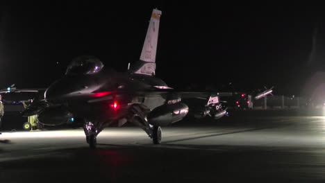 Ein-F16-Kampfjet-Taxis-Auf-Einer-Landebahn-Bei-Nacht