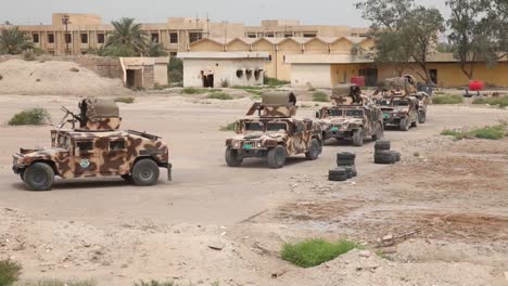 A-Convoy-Of-Military-Vehicles-Moves-Through-A-Destroyed-Region-Of-Iraq