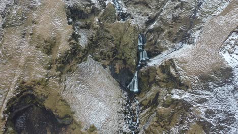 An-aerial-view-shows-a-waterfall-and-its-surrounding-landscape-during-winter-in-Iceland