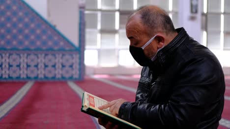 Older-Man-Wears-Mask-And-Reads-The-Quran-In-Mosque