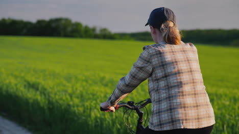 Woman-Rides-Her-Bike-Among-Green-Wheat-Fields
