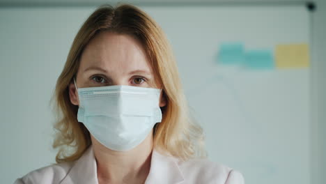 Portrait-Of-A-Teacher-In-A-Medical-Mask-Against-The-Background-Of-A-Classroom-Board