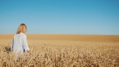 Female-farmer-walks-on-the-boundless-field-of-yellow-wheat