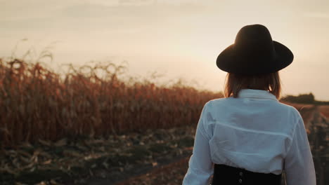 Farmer-in-a-dress-and-hat-walks-in-a-field-of-ripe-corn-10