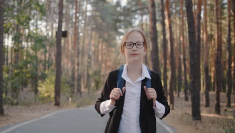 A-child-with-a-back-pack-walks-alone-through-a-park-with-tall-trees-1