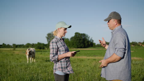 Two-farmers-talk-in-a-pasture-and-use-a-tablet-1