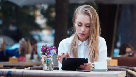 Beautiful-young-woman-uses-a-tablet-in-a-cafe