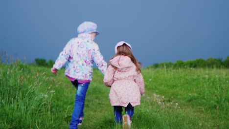 Two-cheerful-girls-run-hrough-the-meadow-holding-hands-1