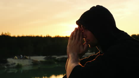 A-young-man-in-a-hood-prays-at-sunset-3