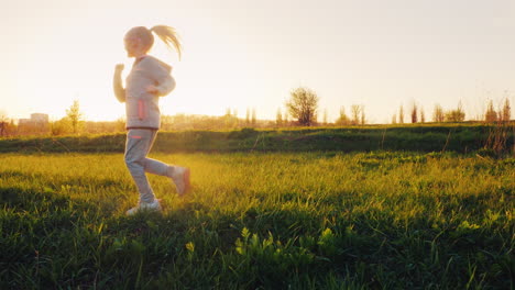 A-6-Year-Old-Girl-Is-Doing-Exercises-On-A-Green-Meadow-At-Sunset