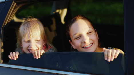 Zwei-Lustige-Mädchen-Im-Alter-Von-6-Und-11-Jahren-Schauen-Aus-Dem-Autofenster