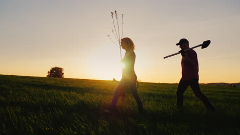 Side-View-Of-Farmers---A-Man-And-A-Woman-Walking-Across-The-Field-At-Sunset