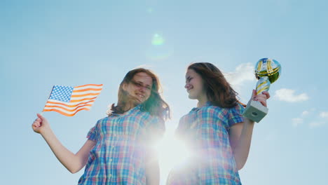 Zwei-Teenager-Zwillingsmädchen-Mit-Einem-Siegerpokal-Und-Einer-Amerikanischen-Flagge