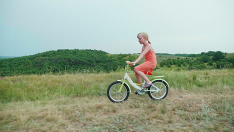 Ein-Cooles-Mädchen-In-Einem-Rosa-Kleid-Fährt-Mit-Dem-Fahrrad-Auf-Dem-Land