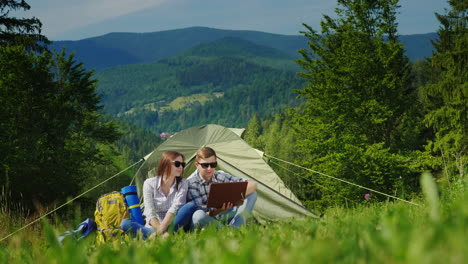A-Young-Couple-Is-Using-A-Laptop-While-Camping-With-A-Tent-1