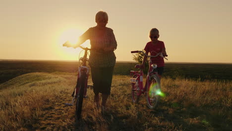 An-Elderly-Lady-Walks-With-Her-Granddaughter-Bicycles-At-Sunset