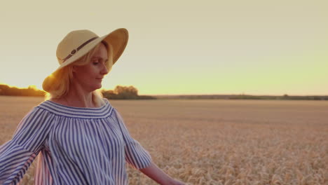 A-Young-Woman-In-A-Hat-Looks-At-The-Sunset-Over-The-Wheat-Field