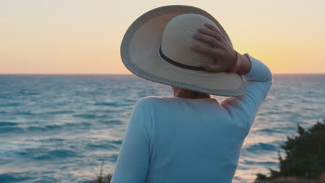 A-woman-in-a-hat-looks-at-the-sunset-over-the-sea