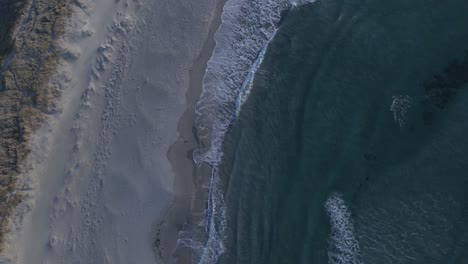 Exotischer-Sandstrand-Mit-Ozeanwellen,-Die-Während-Der-Sonnenuntergangszeit-überrollen,-Luftdrohne-Von-Oben-Nach-Unten